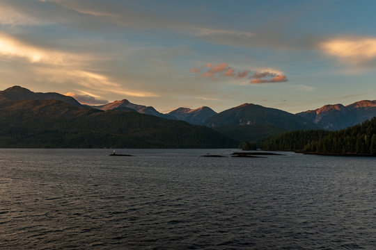The view at sunset from the side of a ferry as it makes its way through the Inside Passage off the rugged west coast of Canada, the light fading in the distance, nobody in the image