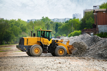 Large yellow wheel loader collects gravel in pile for further loading and transportation. Front wheel loader designed to handle corrosive environments, massive amounts of snow, salt, sand or gravel