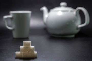 ahead of sugar cube and porcelain mug in background and teapot