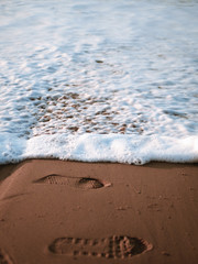 Footstep being washed on the shoreline