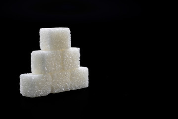Sugar cubes lined up in pyramid shape. Black background