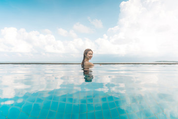Vacations of Woman relax in tropical infinity pool above the beach with beautiful sea in Tropical...