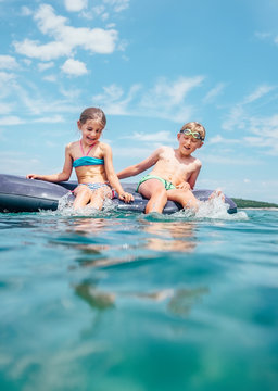 Little brother and sister  sitting  on inflatable mattress in the Adriatic sea. Happy summer holidays concept image.