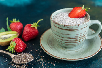 Beautiful and tasty dessert with a kiwi, strawberry and seeds of a chia. A fresh pudding with fruit for breakfast