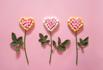 Flower in shape of a heart made of mini marshmallows on pink background. Love concept