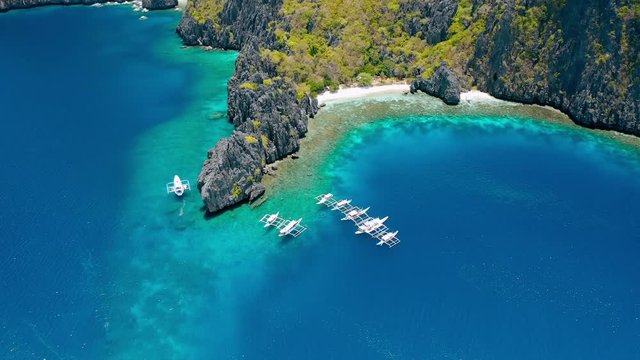 Aerial view of diving boats moored near secret lagoon on Miniloc Island. El-Nido, Palawan. Philippines. Bizarre limestone rock formation and blue lagoon with coral reef make this place unique