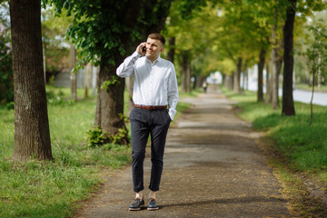 Fototapeta premium Young bisinessman talking on the phone and keeping his hand in the pocket