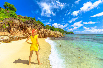 Lifestyle female in yellow looking turquoise sea and pristine white beach of remote Anse La Blague,...