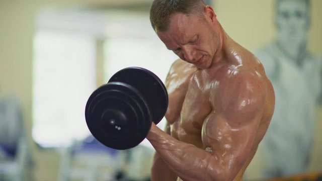Lifting dumbbells for bigger biceps close up. Close up handsome man with big biceps lifting weights