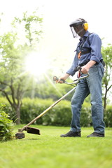 Mann mit Motorsense Freischneider im Garten