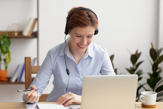 Happy smiling businesswoman in headphones self-study at office desk