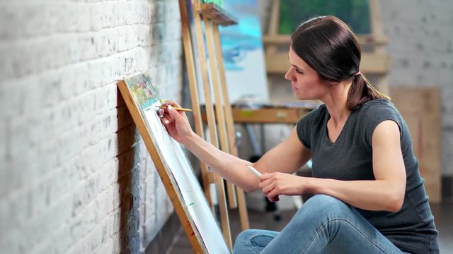 Enthusiastic young woman creating illustration working at art workshop side view