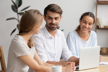 Businesswomen and businessman having informal talk sitting at office desk