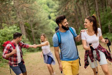 Obraz premium Happy young group hiking together through the forest
