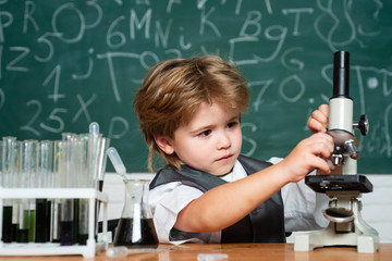 The Science Classroom. Little kid scientist earning chemistry in school lab. Biology lesson. Kid is learning in class on background of blackboard. Experiment.