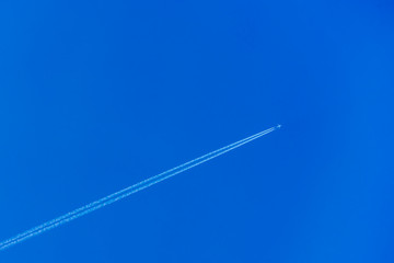 ..Airplane with contrail in the blue sky. The concept of freedom, moving forward. Sky background