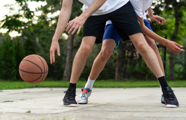Naklejka premium Young mans on basketball court dribbling with ball. Streetball, training, activity