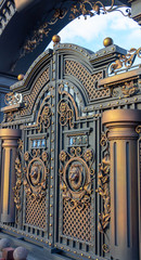 New forged metal massive gates with a wicket and two arches, golden gray, made in antiquity.