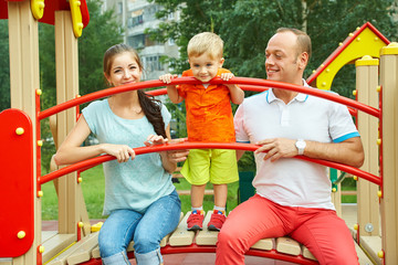 Fototapeta na wymiar child with parents at playground. Mom, dad and son. playing family