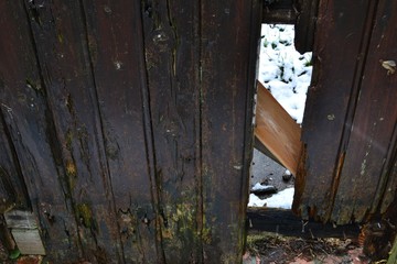 Closeup photograph of a weathered and damaged wooden door.