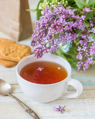 Tea and blooming lilac, petal in a cup
