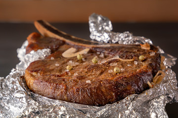 Meat steak baked in foil on a wooden table. Close-up