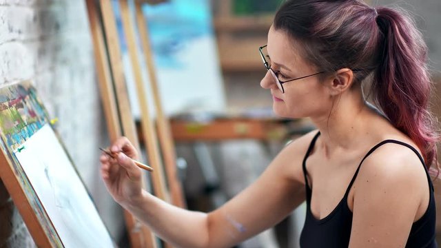 Smiling hipster woman painter making graphic illustration on white paper sheet medium close-up