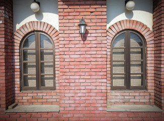 Front view of two vintage rounded window on weathered red brick blocks wall background.