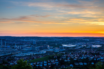 Germany, Red sky over houses of major city stuttgart downtown skyline and popular arena in summer from above