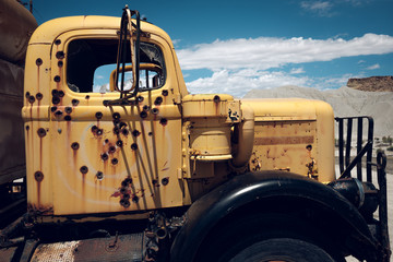 Cab of yellow abandoned truck with bullet holes