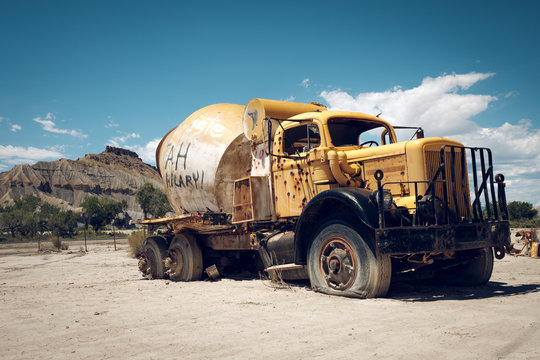 Abandoned cement mixer with bullet holes and graffiti in Utah desert.