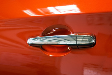 Door handle of a modern red car. Close-up. Detail.