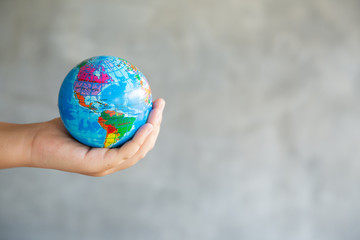 Close-up Portrait of Woman is Holding Global in Her Hands on gray Background. Save The Planet and Traveling Conceptual. Save The Earth and Care Environment Concept.