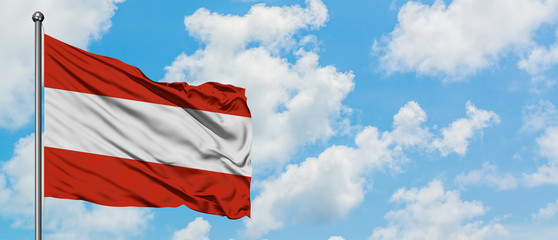 Austria flag waving in the wind against white cloudy blue sky. Diplomacy concept, international relations.