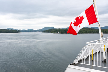 A close up of the Canadian flag flying in the wind at the back of ferry as the boat makes it way through the Inside Passage, British Columbia, Canada, nobody in the image