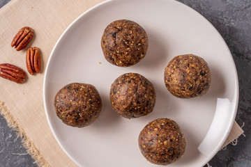 Healthy organic energy balls made with dates, prunes, raisins, peanut, in a plate on gray background.