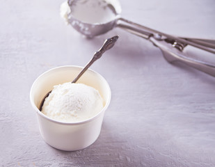 Paper bowl with ice cream with gray napkin and on a gray table