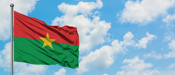 Burkina Faso flag waving in the wind against white cloudy blue sky. Diplomacy concept, international relations.