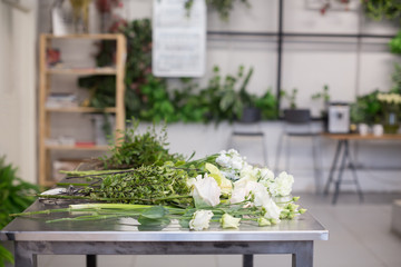 Beautiful white flowers and florist's tools lie on a glossy gray table. Concept of master class for making beautiful flower bouquets