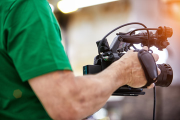 Videographer shooting a film or a television program in a studio with a professional camera, backstage