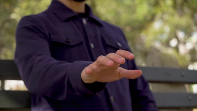 Hand of man sitting on the bench in a park man waving his hand in the air imagining that he presses the keys