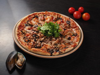 Tasty pizza with seafood and tomato on dark background
