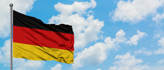 Germany flag waving in the wind against white cloudy blue sky. Diplomacy concept, international relations.