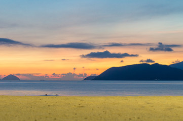 Horizon at colorful sunrise on the beach with yellow sand and blue sky