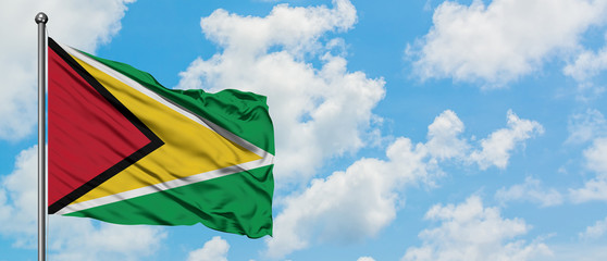 Guyana flag waving in the wind against white cloudy blue sky. Diplomacy concept, international relations.