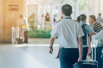 Passengers with big roller luggage stand to wait for the car to pick up at airport arrival terminal.