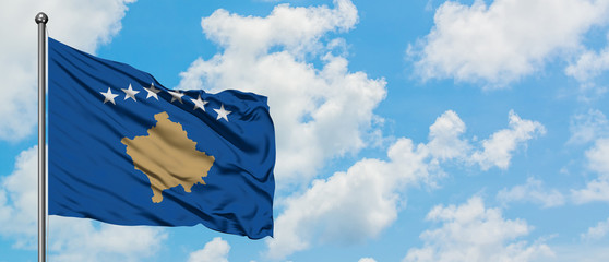 Kosovo flag waving in the wind against white cloudy blue sky. Diplomacy concept, international relations.