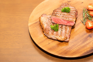 Fresh cooked half cut beef sirloin with cherry tomato and rosemary on top with parsley, Wood background