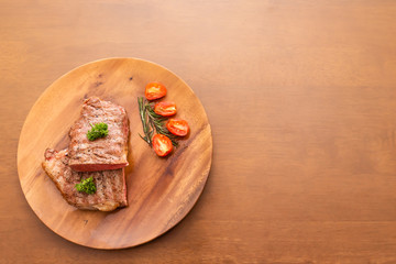 Fresh cooked half cut beef sirloin with cherry tomato and rosemary on top with parsley, Wood background, Copy space on the right