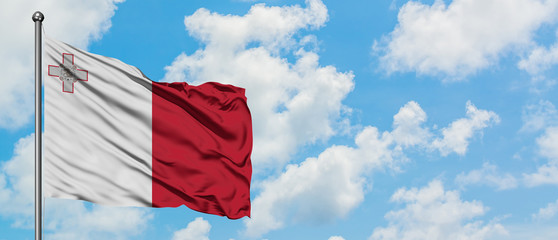 Malta flag waving in the wind against white cloudy blue sky. Diplomacy concept, international relations.